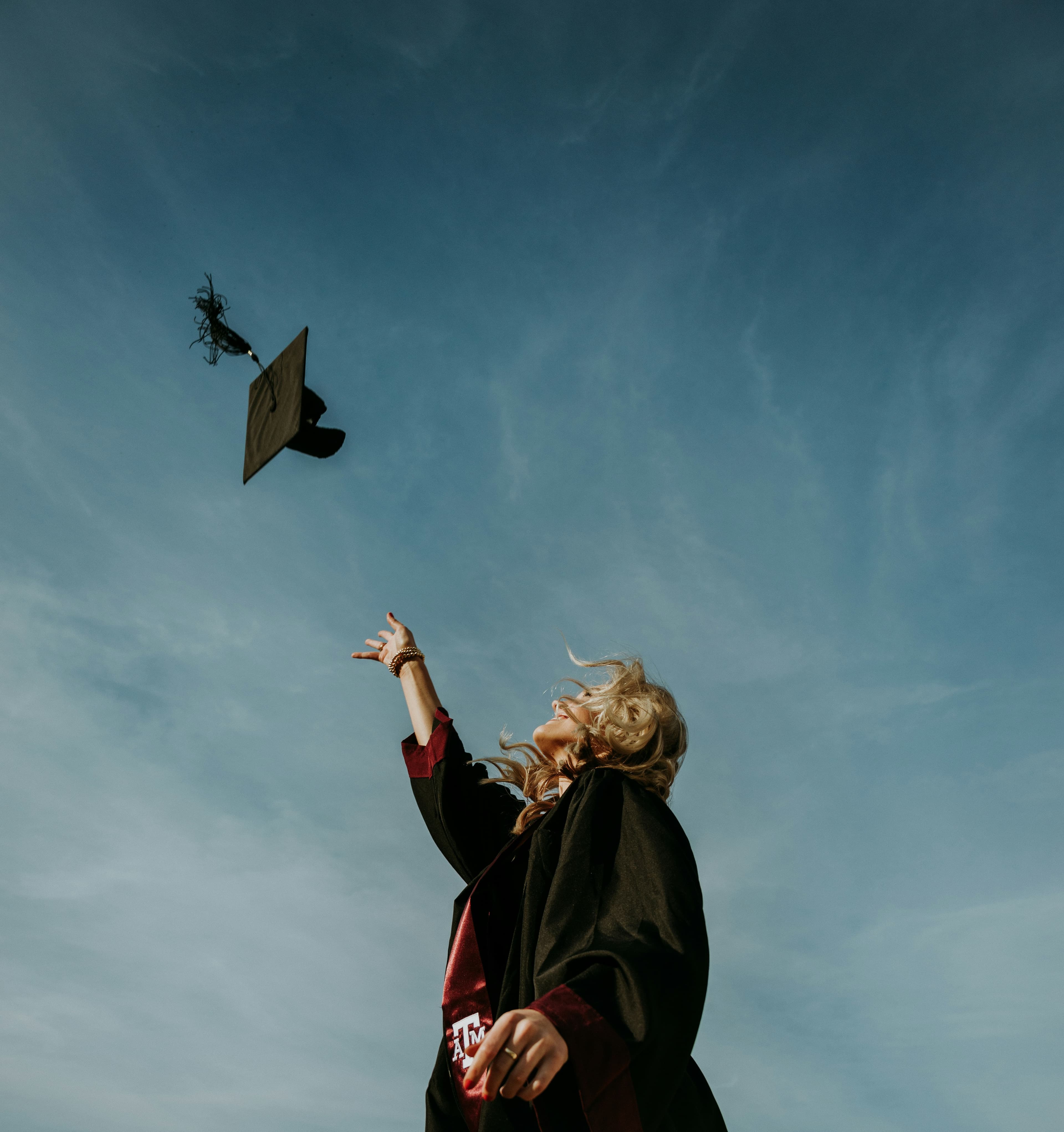 Student celebrating graduation, tossing her cap into the sky