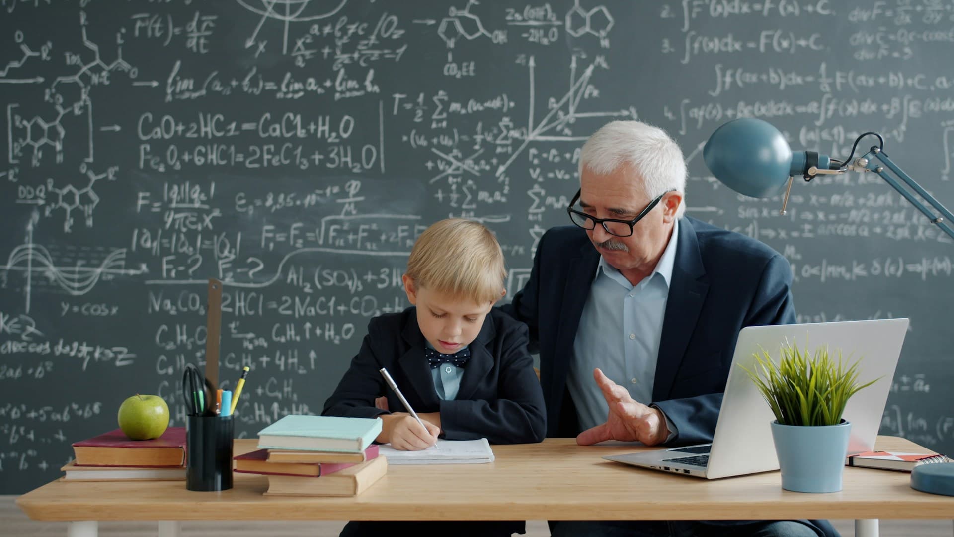 A tutor guiding a young student through his work one-on-one at a desk